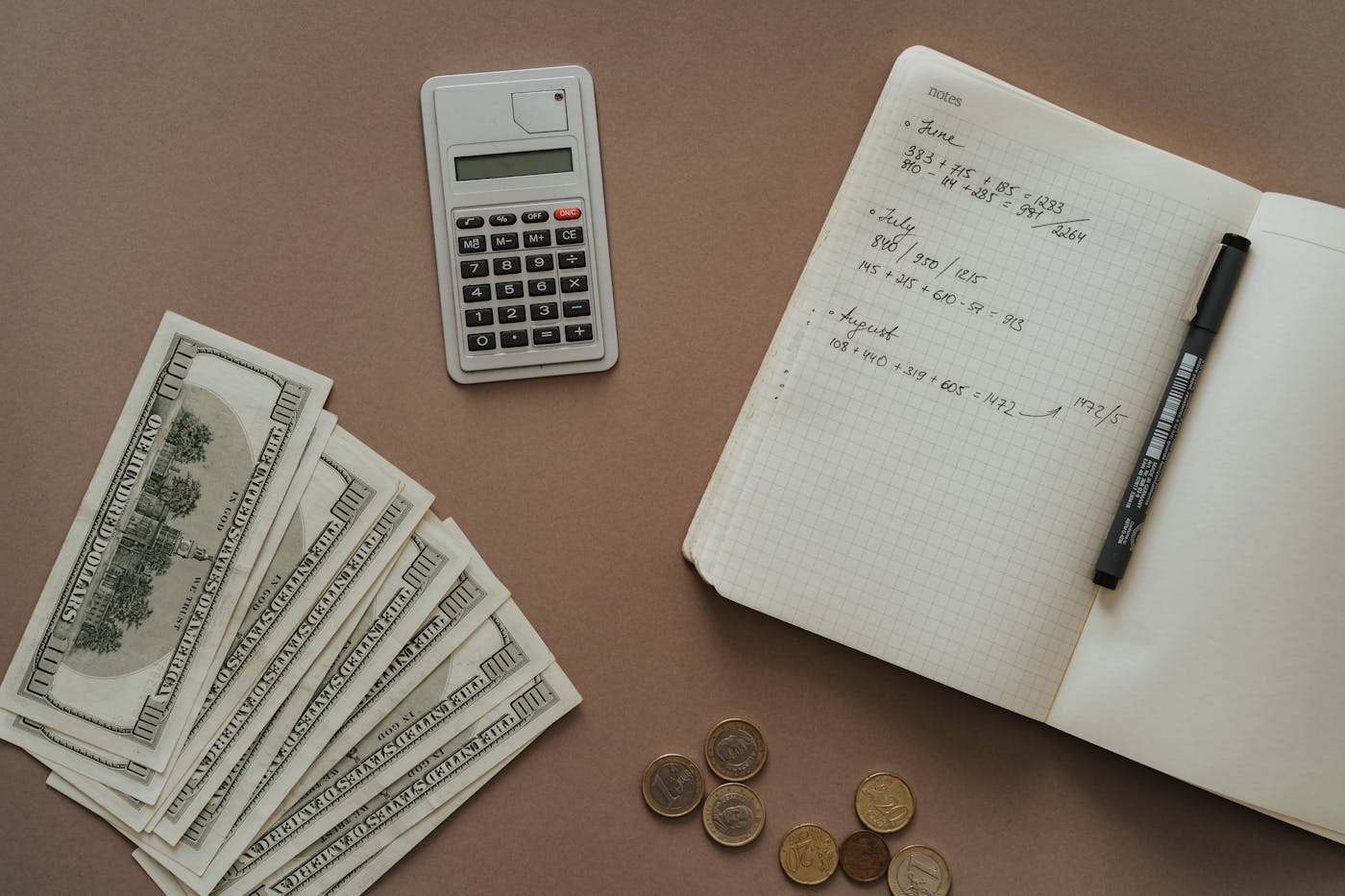 電卓とノートと紙幣で貯金計画を立てるデスク